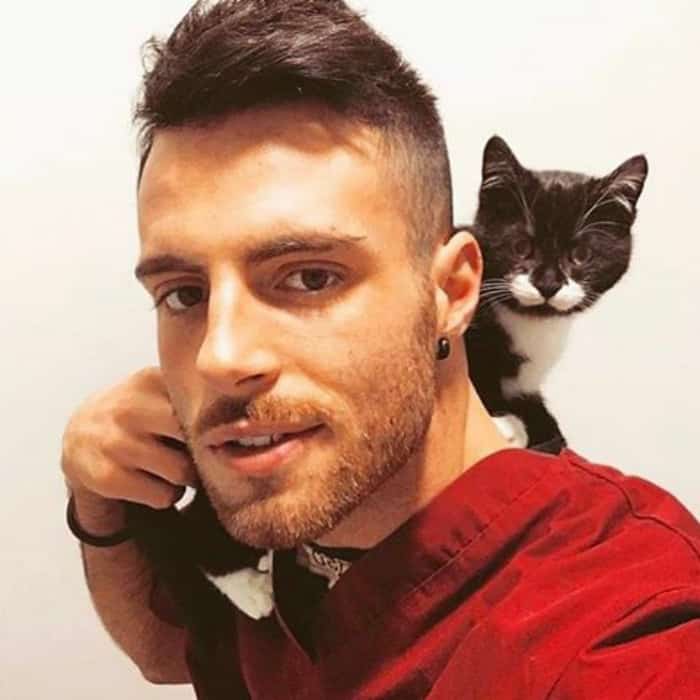 парень в красной рубахе держит на плечах котенка