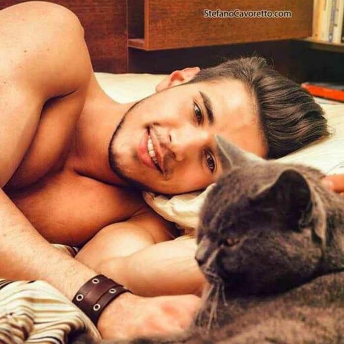 парень лежа смотрит на серого кота