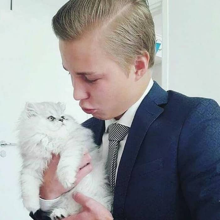блондин в галстуке хочет поцеловать белого котенка