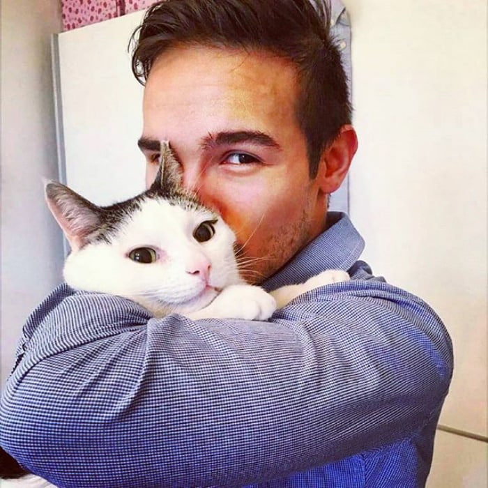 парень в серой рубахе целует кота